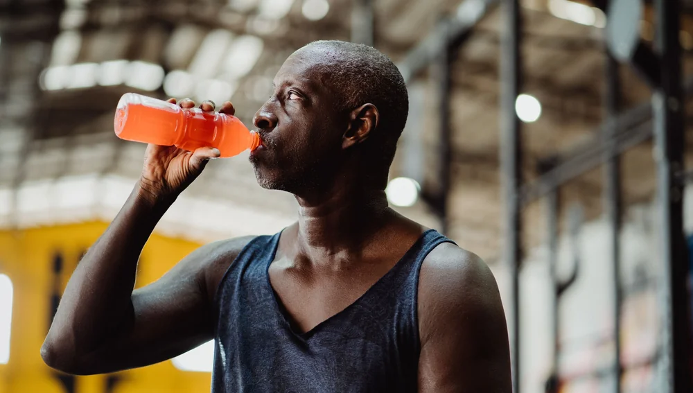 Atlet pria minum minuman energi saat latihan gym - artikel minuman serbuk kebugaran olahraga Yasma Natura