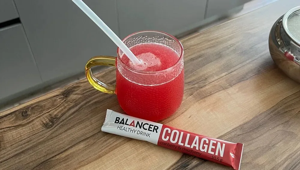 Minuman collagen cranberry raspberry dalam gelas di atas meja kayu